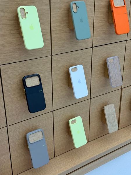 A wall of solid-colour phone cases on wooden display pegs